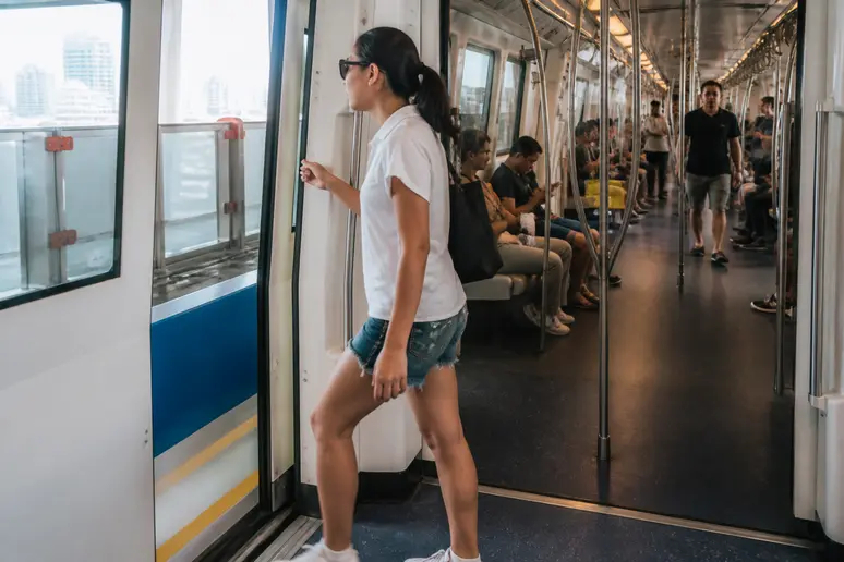 Eine thailändische Frau steigt in einen klimatisierten Skytrain in Bangkok ein, um dem Verkehr zu entgehen und die Stadt zu erkunden.