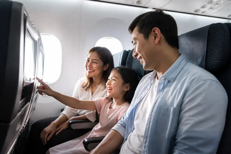 Eine Familie genießt den Flug in der Economy Class eines modernen Dreamliners mit individuellen Bildschirmen zur Unterhaltung.