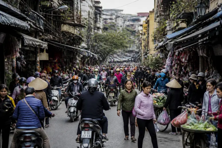 Lebhaftes Treiben in der Altstadt von Hanoi mit vielen Einheimischen bei alltäglichen Aktivitäten und Einkäufen, was die hohe Bevölkerungsdichte und das städtische Leben widerspiegelt.