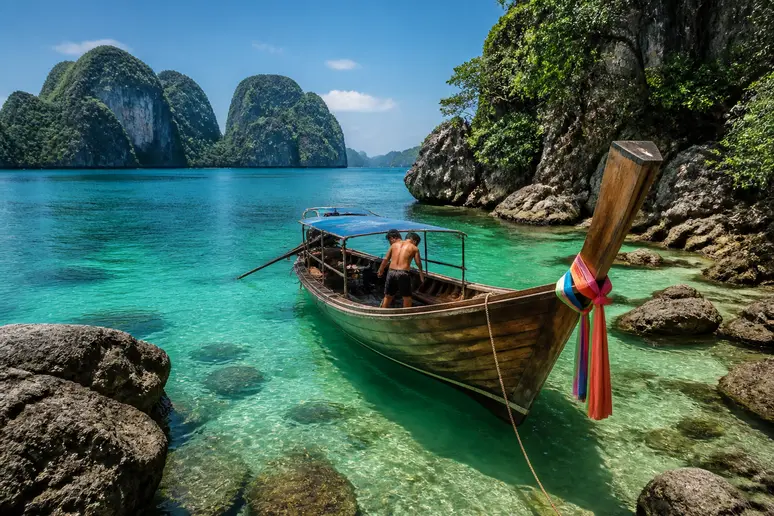 Ein Thai Longtail-Boot ankert vor der atemberaubenden Maya Bay, umgeben von Kalksteinfelsen und türkisfarbenem Wasser.
