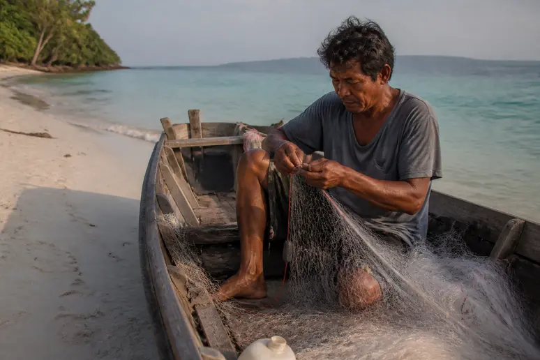 Fischer repariert sein Netz auf Koh Rong Kambodscha mit türkisfarbenem Wasser.