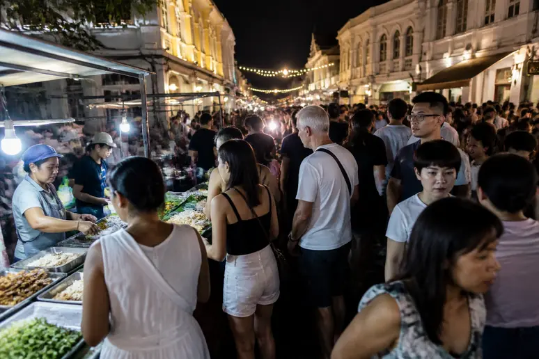 Lebhafter Nachtmarkt in Phuket-Stadt mit vielfältigem Streetfood-Angebot und einer fröhlichen Menschenmenge, die die kulinarische Vielfalt genießt.