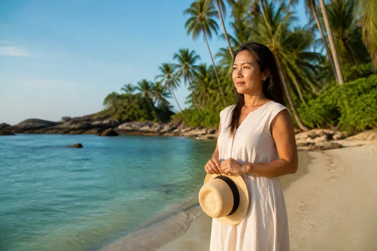 Entspannte Frau am Strand von Thailand denkt über Reisezeit nach – Aleenta Resorts Phuket Hua Hin.