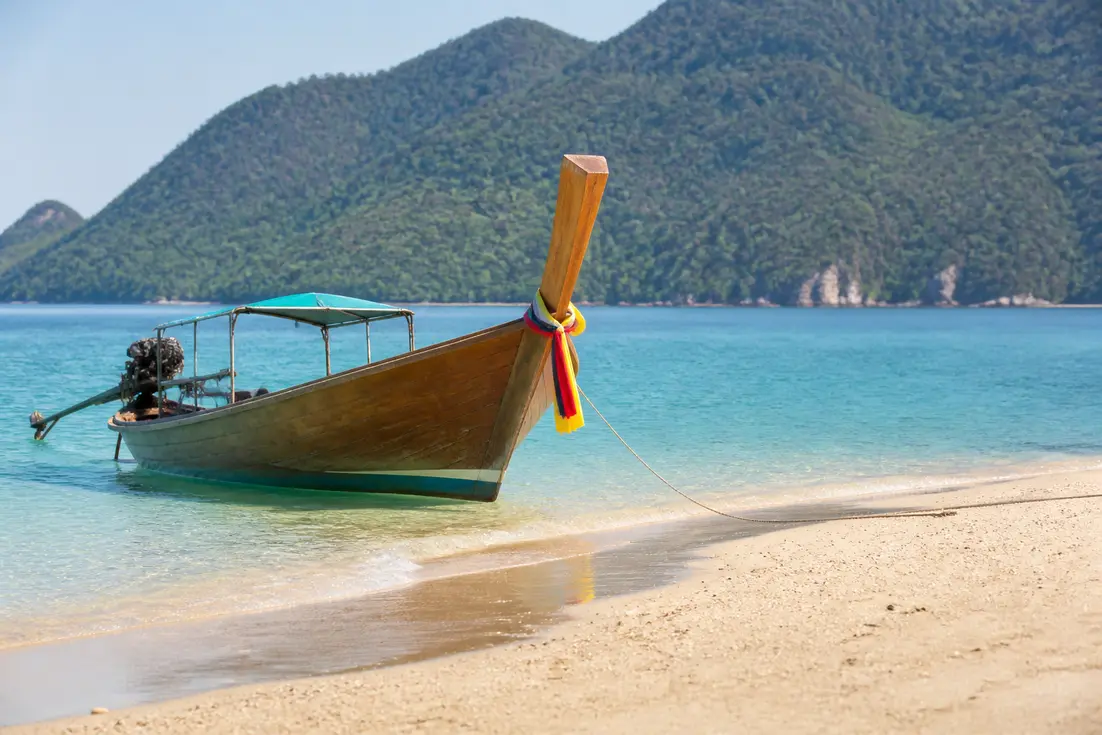 Traditionelles Holzboot an einem ruhigen Strand als idealer Ort für Klima Thailand beste Reisezeit