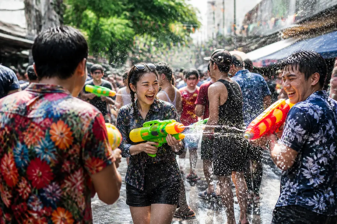 Fröhliche Menschen feiern das Songkran beste Orte Thailand auf einer belebten Straße mit Wasserspielen