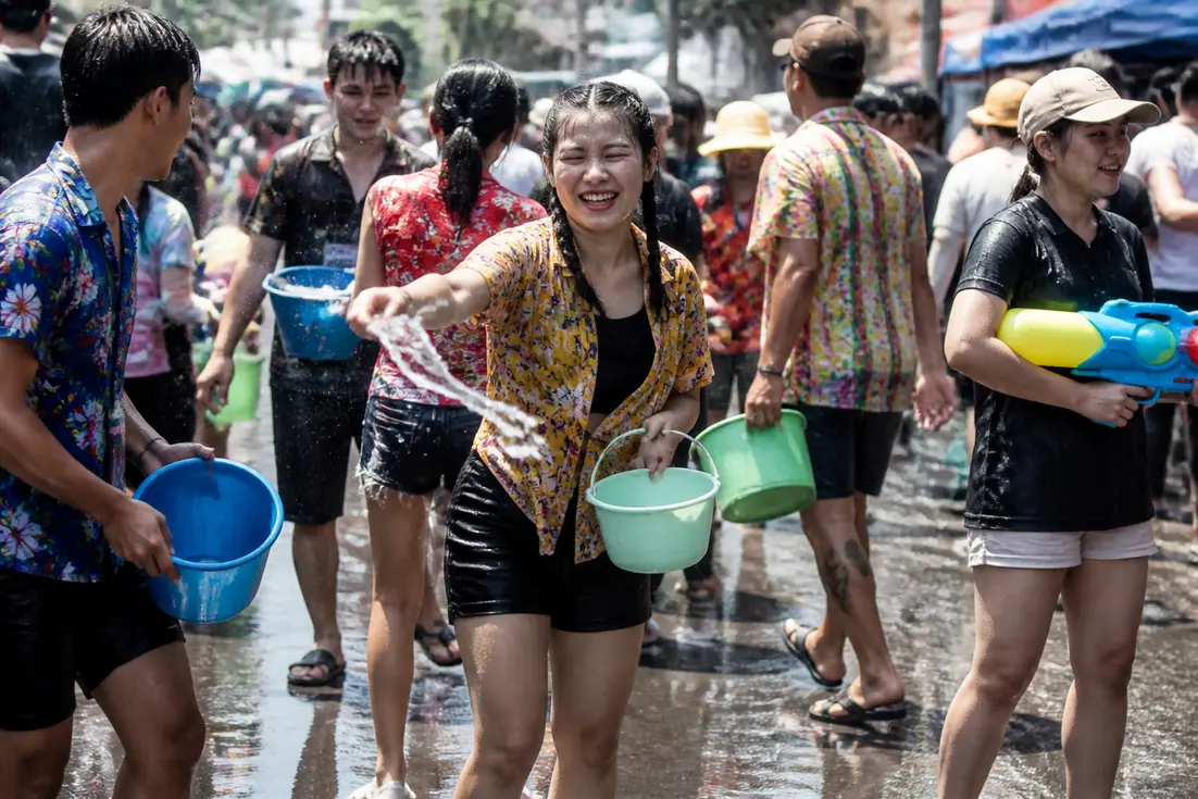 Menschen feiern fröhlich das Songkran-Neujahrsfest mit Wasserspielen auf einer Straße in Thailand im April.