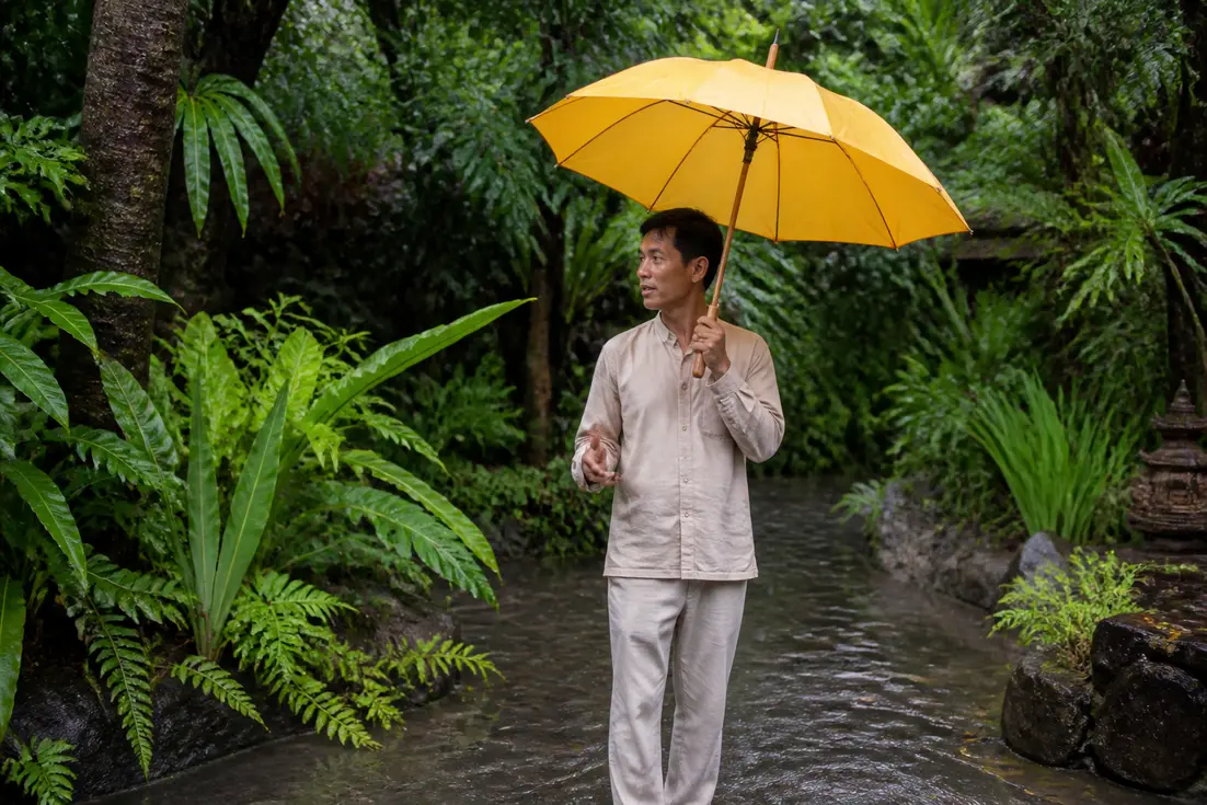 Reiseleiter mit Regenschirm im tropischen Garten zeigt das Wetter Thailand Juni