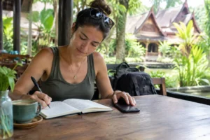 Reisender sitzt in einem thailändischen Café und nutzt die beste esim thailand für die Reiseplanung