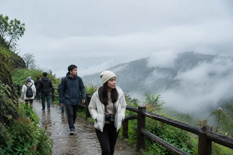 Wanderer in leichten Jacken auf dem nebligen Gipfelpfad im Doi Inthanon Nationalpark