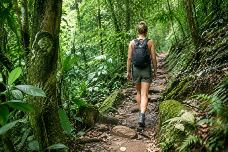 Wanderer auf einem schmalen Pfad im dichten tropischen Dschungel des Erawan-Nationalparks