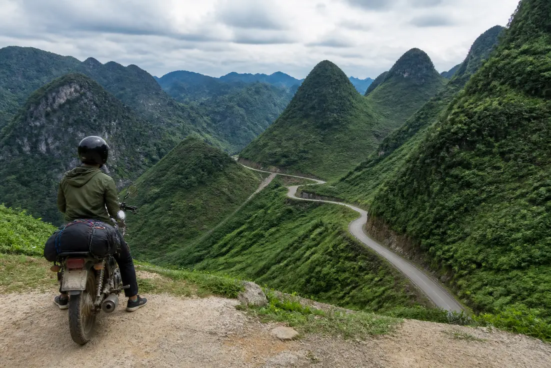 Ein Reisender auf einem Motorrad bewundert die bergige Landschaft beim ha giang loop