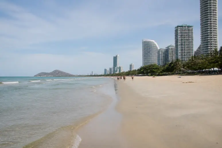 Weitläufiger und ruhiger Sandstrand mit flachem Wasser an der Küste von Cha-Am.
