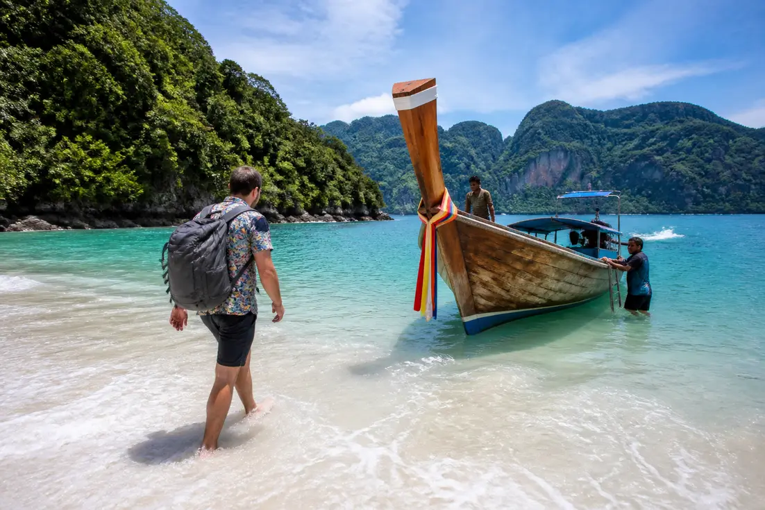 Traditionelles Longtailboot am malerischen Sandstrand für den Ko Muk Urlaub in Thailand