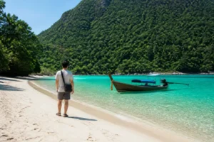 Koh Adang Reisetipps zeigen die malerische Küste mit einem Longtail-Boot im klaren Wasser.