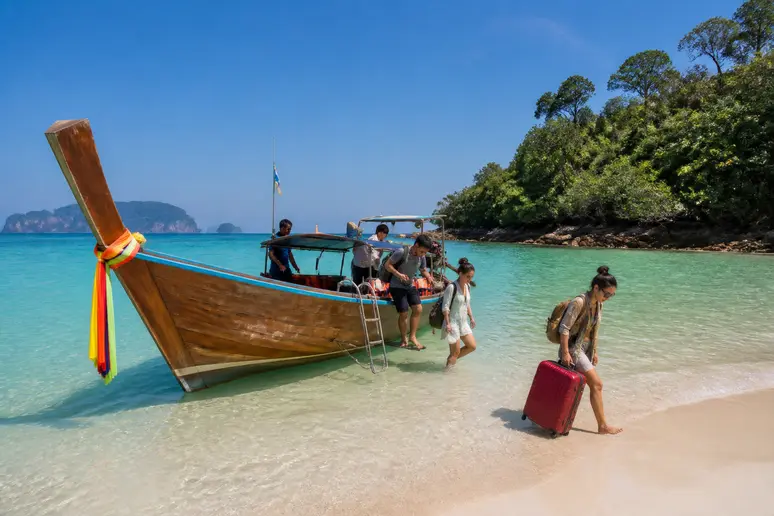 Lokales Holzboot bringt Reisende an den flachen Sandstrand der ruhigen Insel Koh Bulon
