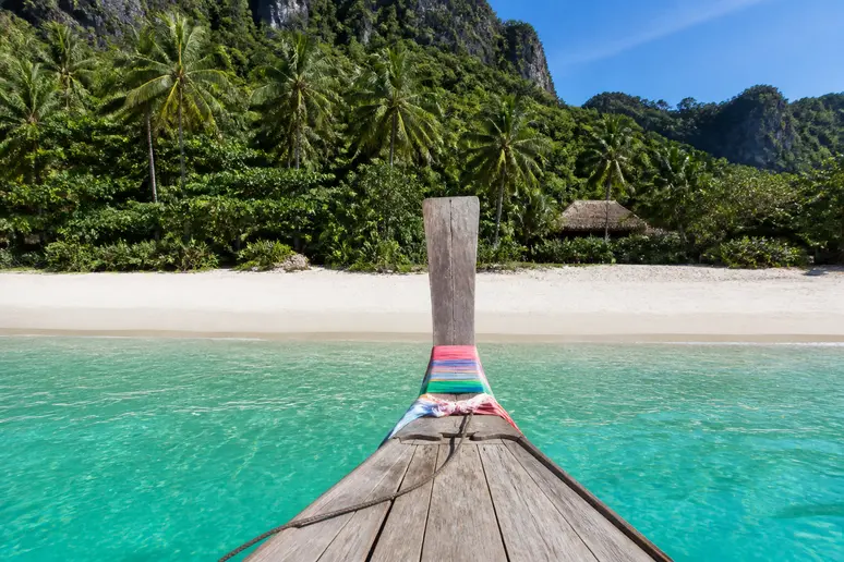 Traditionelles Longtailboot vor dem weißen Sandstrand und dem klaren Wasser für die Koh Kradan Reise