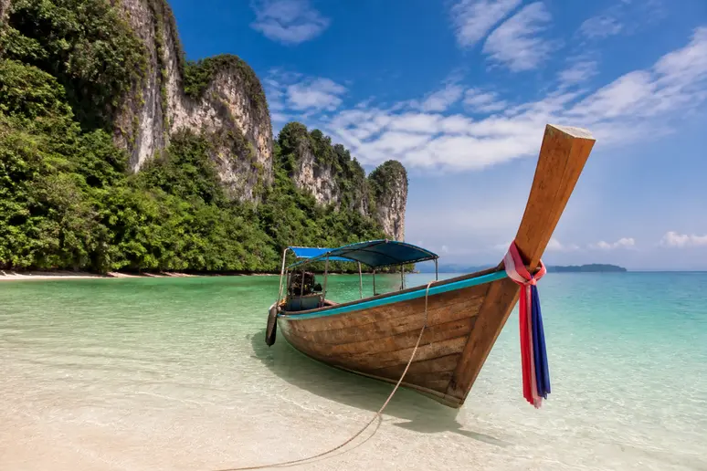 Traditionelles Longtailboot im flachen Gewässer vor einer tropischen Insel während einer Koh Libong Reise