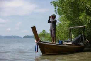 Ein Reiseleiter mit Fernglas auf einem Longtail-Boot im Rahmen eines Koh Libong Reiseführer