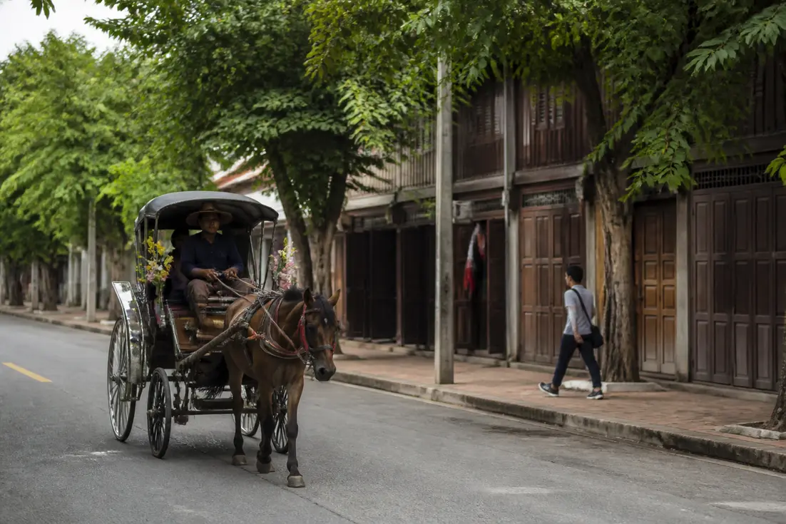 Traditionelle Pferdekutsche fährt durch eine Straße in lampang thailand vorbei an historischen Holzhäusern