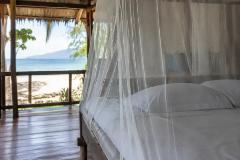 Feines Moskitonetz über einem Bett in einem thailändischen Strandbungalow als wirksamer Mückenschutz