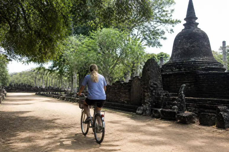 Radfahrer auf einem sandigen Weg zwischen antiken Ruinen in Polonnaruwa