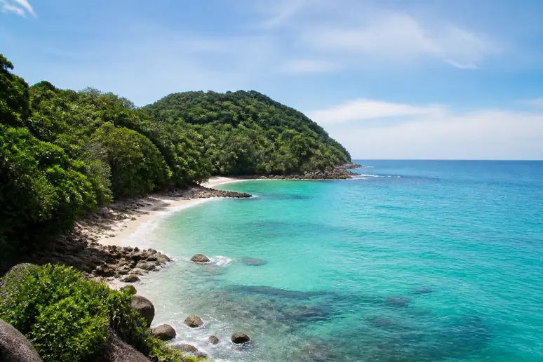 Abgelegener tropischer Strand auf Phuket umgeben von grünem Dschungel und klarem Wasser