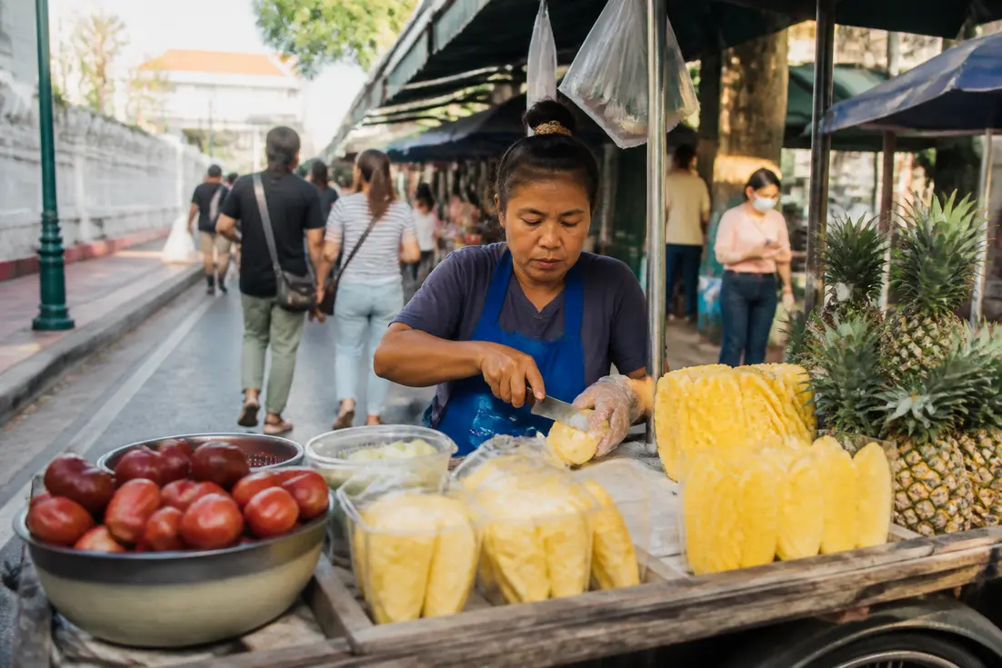Einheimischer Händler bereitet frische Früchte an einem Straßenstand in thailand krung thep vor.