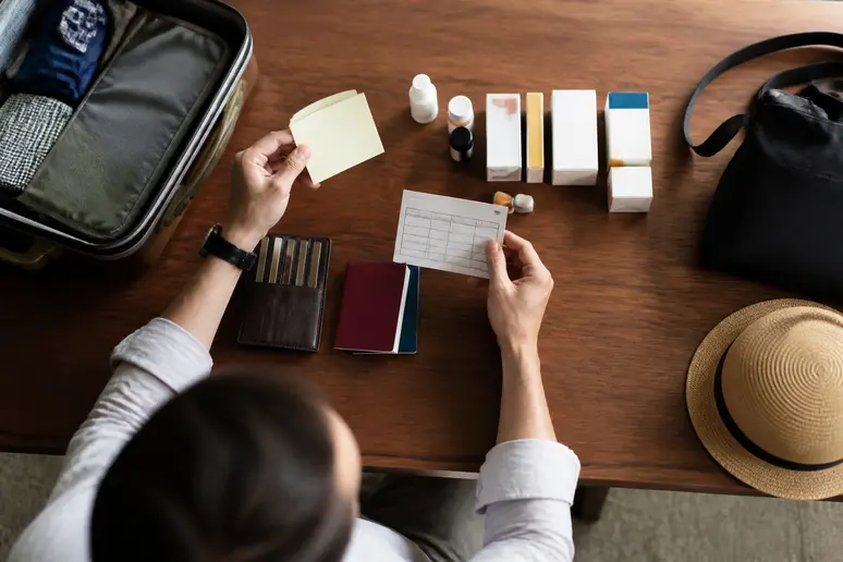 Organisierte Medikamente und Gesundheitsunterlagen für die Reisevorbereitung auf einem Schreibtisch
