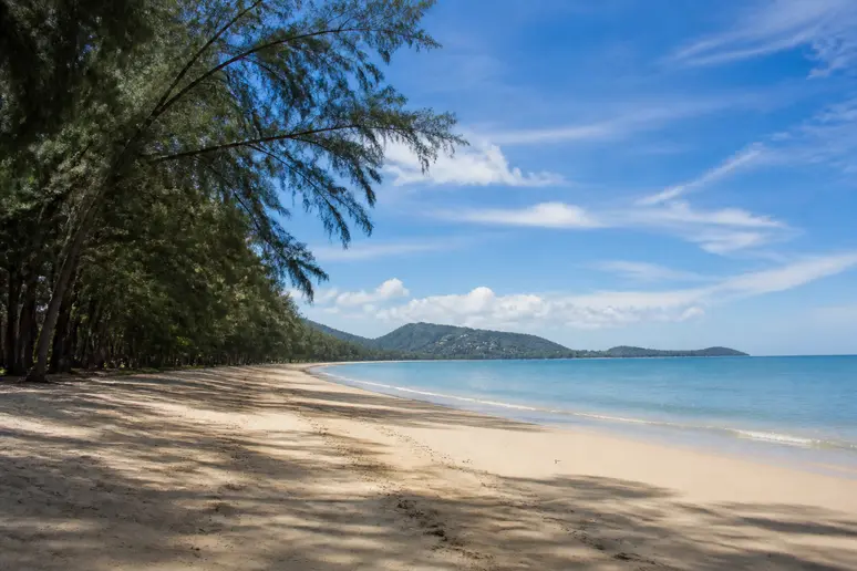 Ruhiger und naturbelassener Sandstrand im Norden Phukets mit schattigen Bäumen