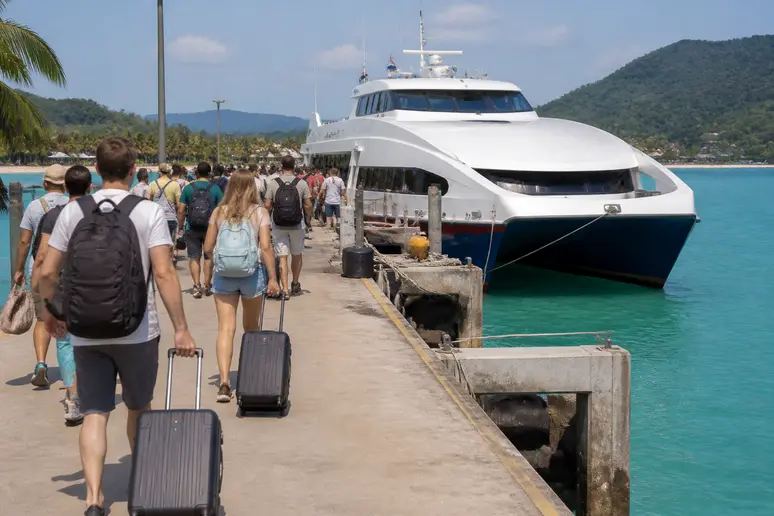 Reisende mit Gepäck am Fähranleger vor der Überfahrt nach Koh Kood