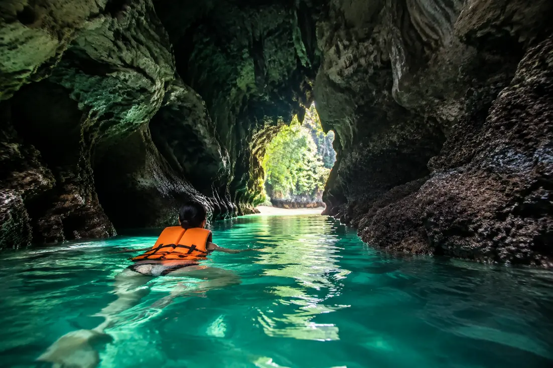 Schwimmer erkundet mit Schwimmweste den dunklen Höhleneingang zur emerald cave auf Koh Mook