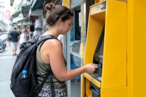 Tourist verwendet geld abheben thailand an einem gelben Bankomaten auf einer belebten Strasse