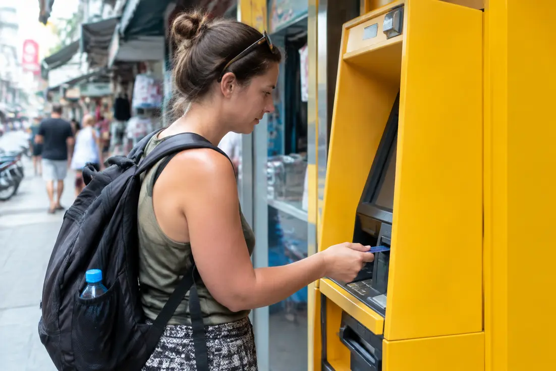 Tourist verwendet geld abheben thailand an einem gelben Bankomaten auf einer belebten Strasse