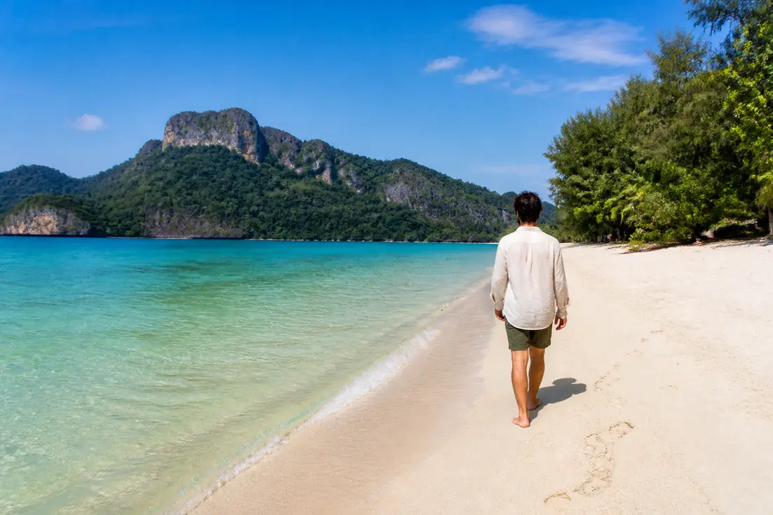 Klima Koh Chang beste Reisezeit an einem sonnigen Strand mit klarem Wasser und grünem Dschungel.