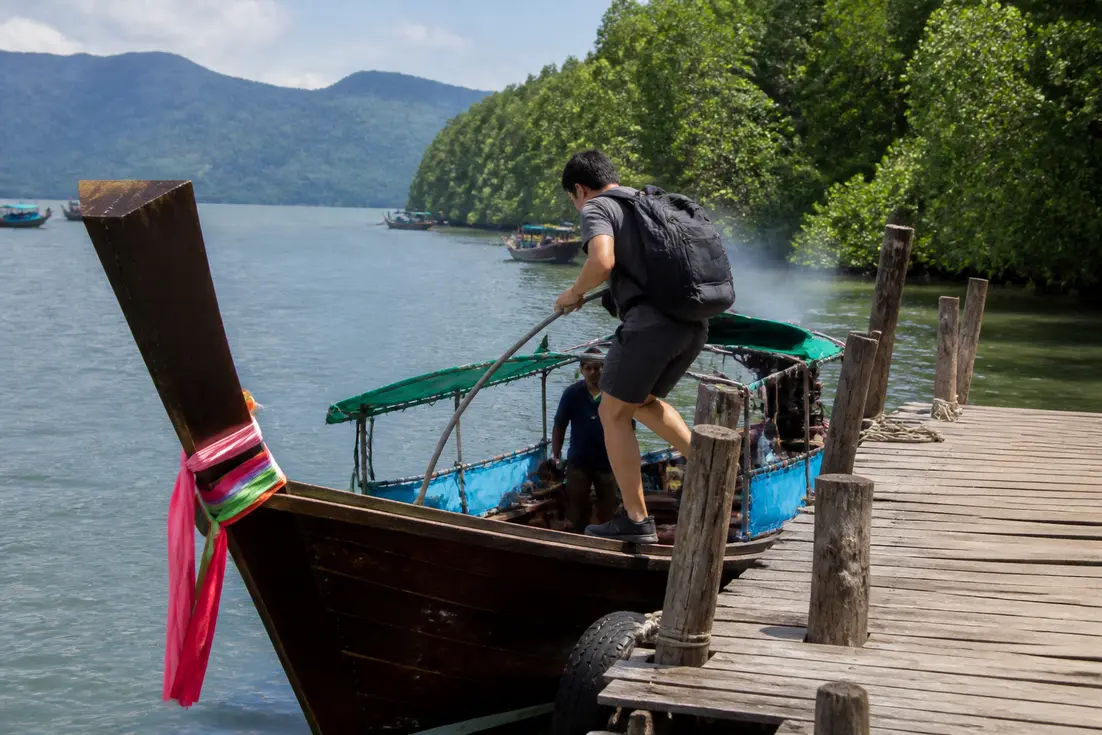 Ein Reisender besteigt ein Holzboot für den Koh Chang Ranong Reiseführer in Thailand.