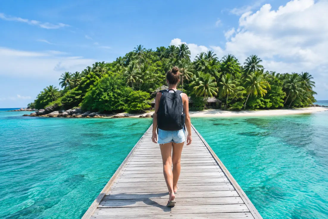 Besucher spazieren über einen Holzsteg mit Blick auf die malerische koh kham island im türkisblauen Meer.