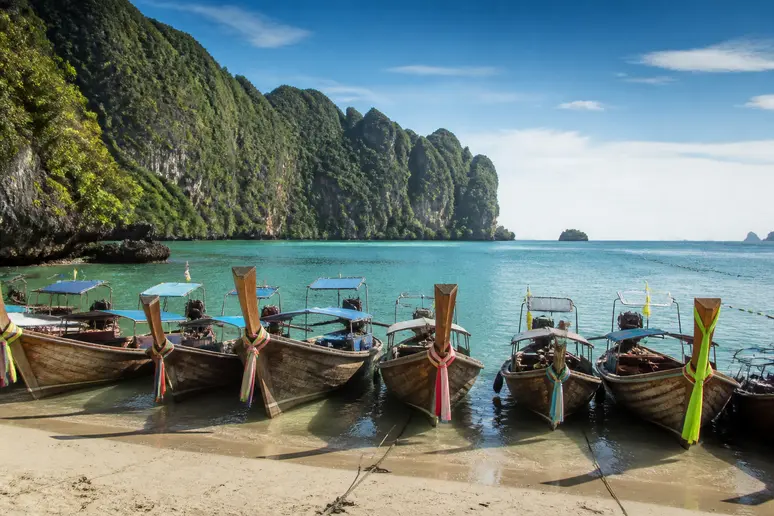 Traditionelle Longtail-Boote an einem ruhigen Küstenabschnitt in Krabi für Reisetipps