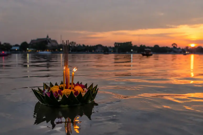 Traditionelles Loy Krathong Lichterfest mit brennenden Kerzen auf dem Wasser eines Flusses
