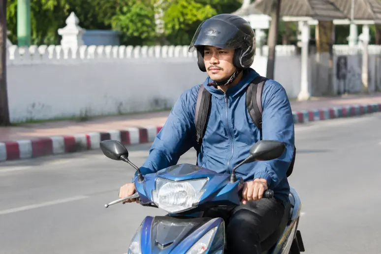 Motorradfahrer mit Schutzhelm im thailändischen Straßenverkehr